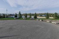 a parking lot in the middle of a residential area with grass and trees in the background