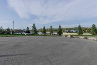 a parking lot in the middle of a residential area with grass and trees in the background