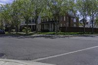 an empty street in a residential area with houses and trees growing along it in the daytime