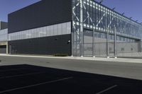 the empty parking lot of an industrial warehouse with glass doors on one side and metal bars on one side