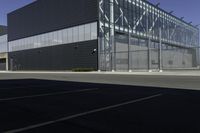 the empty parking lot of an industrial warehouse with glass doors on one side and metal bars on one side