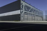 the empty parking lot of an industrial warehouse with glass doors on one side and metal bars on one side