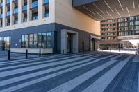 an empty street with a large glass building and a city sidewalk in the background with pedestrians