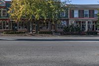 a street with green buildings and two stores on both sides of the road and trees lining the sidewalk