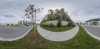 this is a fish eye view of a road with buildings in the background and a tree on the right side