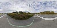 a street and a road next to each other under a cloudy blue sky as a fish eye lens