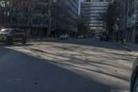 an empty city street with cars driving in the sun and people walking on the sidewalk