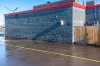 a building on the side of a road in front of an empty parking lot where people are sitting and walking in