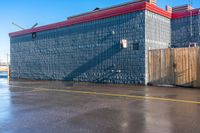 a building on the side of a road in front of an empty parking lot where people are sitting and walking in