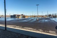 a long street near a parking lot under blue skies and snow on the ground with a sign in it