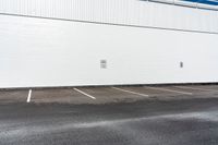 a white building with white lines painted on it in the parking lot near a street