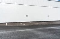 a white building with white lines painted on it in the parking lot near a street