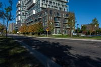 a tall building sitting on the side of a street next to trees and grass with a blue sky above