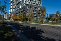 a tall building sitting on the side of a street next to trees and grass with a blue sky above