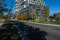 a tall building sitting on the side of a street next to trees and grass with a blue sky above