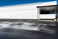 an empty lot with a large white building in the background and parking spaces on either side