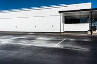 an empty lot with a large white building in the background and parking spaces on either side