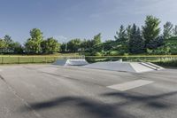 a skate park has some ramps in the area near trees and grass, as seen on this view