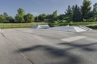 a skate park has some ramps in the area near trees and grass, as seen on this view