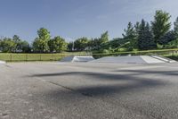 a skate park has some ramps in the area near trees and grass, as seen on this view