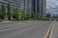 the empty street has white markings on it and is lined with trees and apartment buildings