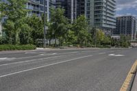 the empty street has white markings on it and is lined with trees and apartment buildings