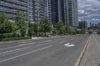 a paved road near two tall buildings in an urban setting with green trees and shrubs