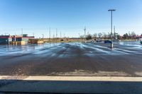 cars parked on a wet parking lot in front of a large building with parking spaces