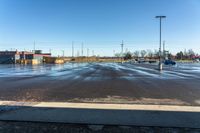 cars parked on a wet parking lot in front of a large building with parking spaces