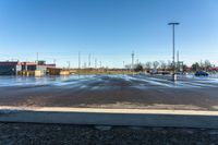 cars parked on a wet parking lot in front of a large building with parking spaces