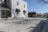 a sidewalk is in the middle of a street with a store and a dog walking near the doorway