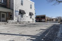 a sidewalk is in the middle of a street with a store and a dog walking near the doorway