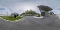 this is the view from a fish eye view of the corner of an oval, grey building on a street