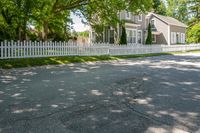 a white house with a white picketed fence on the side and grass behind it