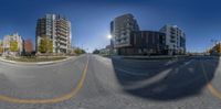 an empty street with three buildings in the background as seen through a fish eye lens