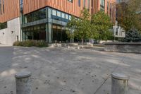 a courtyard with concrete steps next to trees and building entrance on a sunny day outside