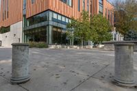 a courtyard with concrete steps next to trees and building entrance on a sunny day outside