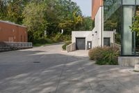 the walkway is made up of cement slabs and plants next to the building with large glass windows