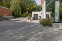 the walkway is made up of cement slabs and plants next to the building with large glass windows