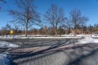 the intersection of the road in a public park with no cars on it, and a yellow fire hydrant at the end