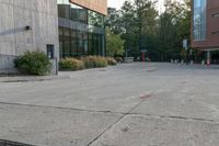 a sidewalk in front of a building next to a park with trees, bushes and people