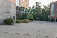 a sidewalk in front of a building next to a park with trees, bushes and people