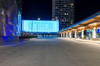 the empty walkway of a city train station at night with blue lights on its side