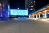 the empty walkway of a city train station at night with blue lights on its side