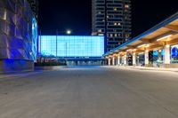 the empty walkway of a city train station at night with blue lights on its side