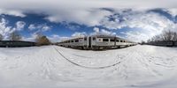 a train on tracks surrounded by snow and trees under a cloudy sky in winter season