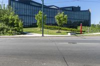 a building that is near trees and grass on a street corner for pedestrians to pass