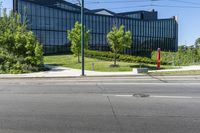 a building that is near trees and grass on a street corner for pedestrians to pass