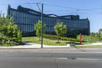 a building that is near trees and grass on a street corner for pedestrians to pass