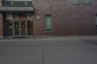 an empty fire hydrant stands in front of a brick building with no cars on it